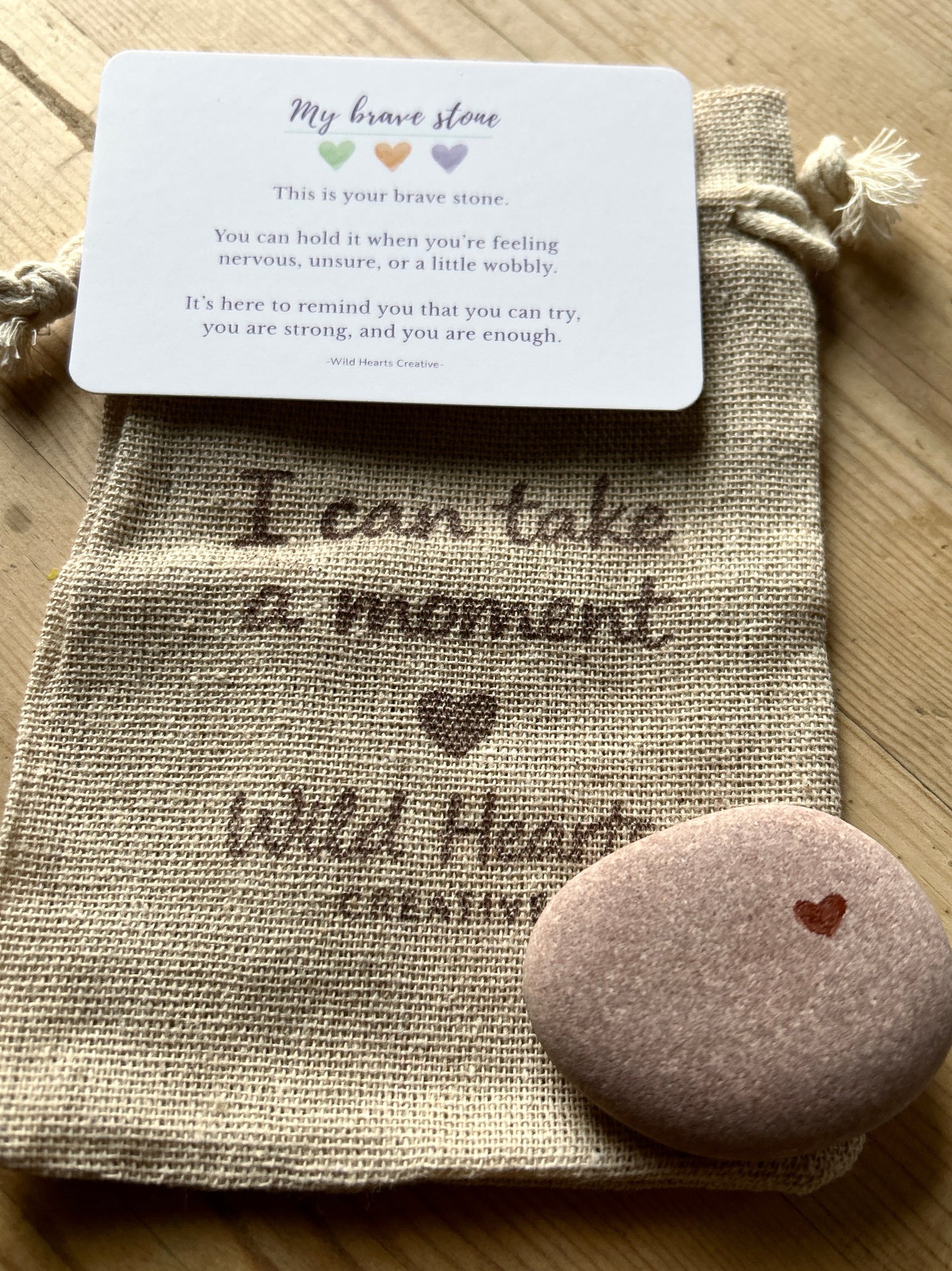 Decorative stone with bravery text and a card on a textured surface for children branded by wild hearts creative