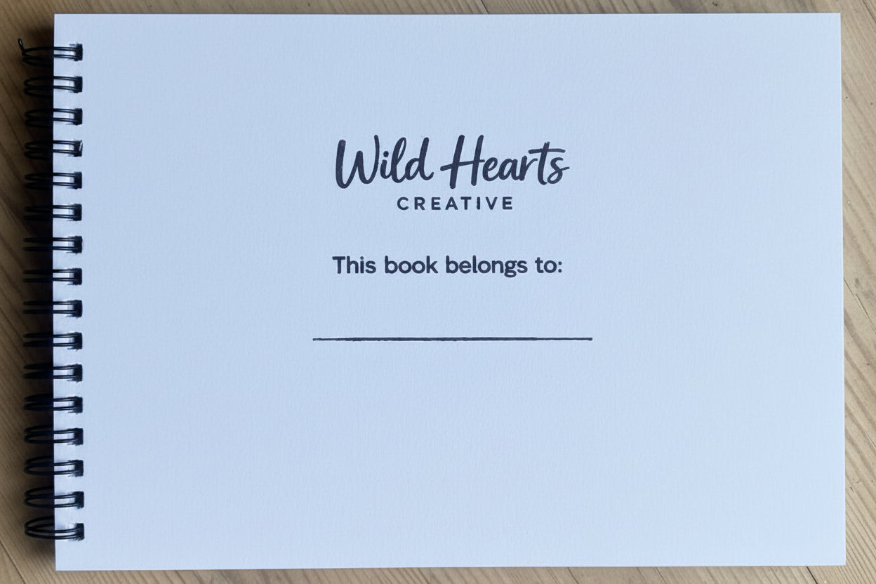 Notebook with 'Wild Hearts Creative' branding on a wooden surface.  Hand stamped for important moments