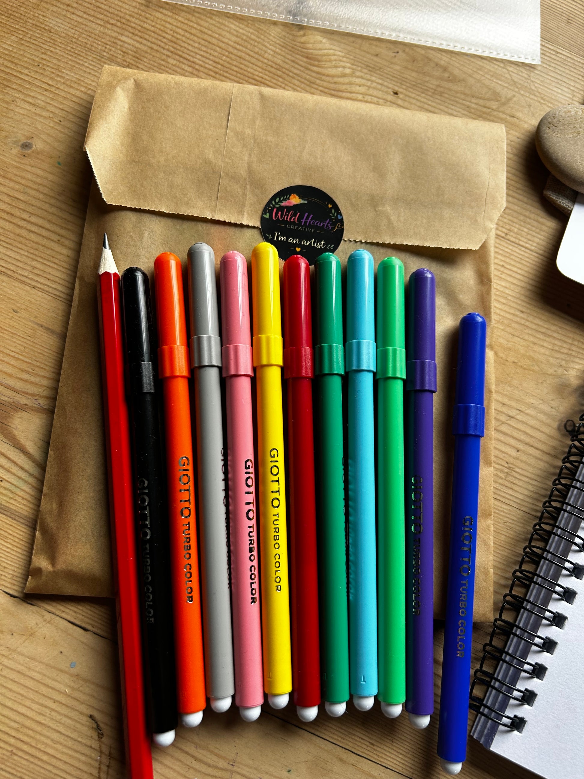 Set of Giotto Turbo Color pens in various colors on a wooden surface.