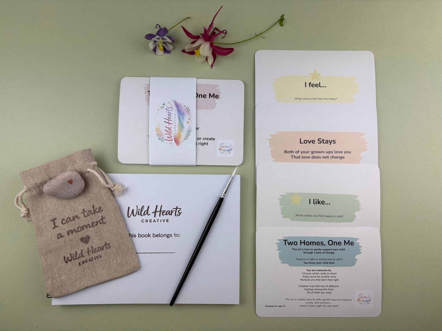 Flat lay of the Two Homes, One Me divorce and separation creative support kit for children, featuring prompt cards, comfort stones, creative resources and comfort items designed to support emotional wellbeing.