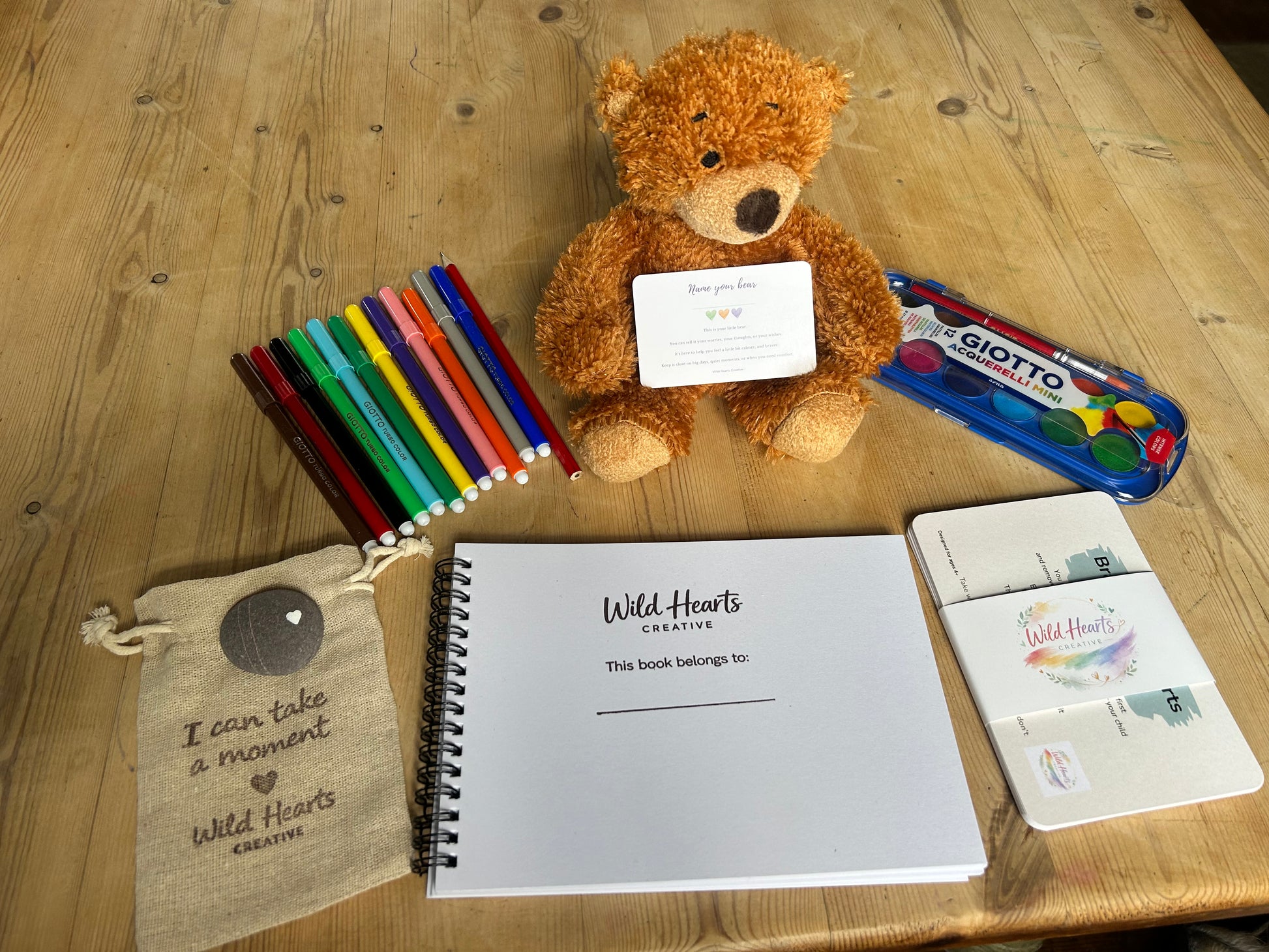Wild Hearts Creative, clean flat lay kit of Little Brave Hearts, worry name your bear, pens, comfort stone, affirmation and gentle prompt cards, sketchbook and watercolours
