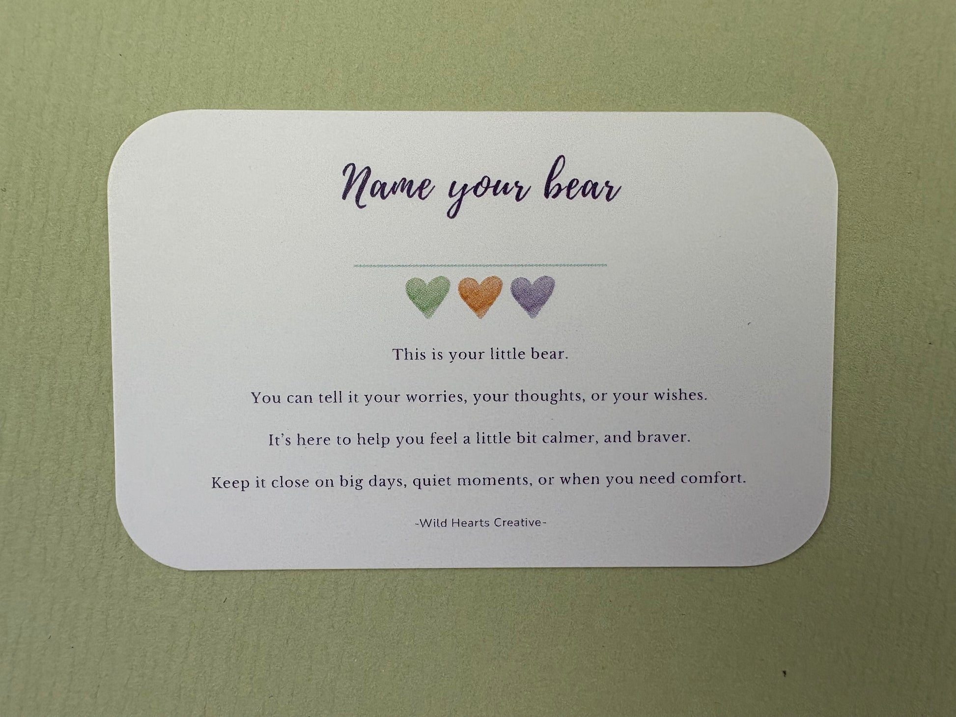 Card with 'Name your bear' text and heart illustrations on a green background
