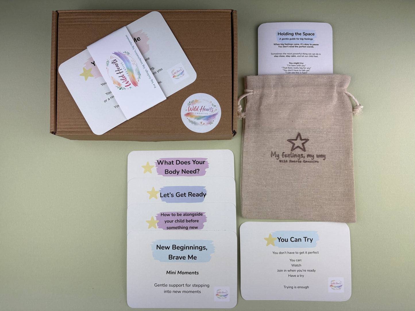 Flat lay of the New Beginnings, Brave Me Mini Moments support kit for children, featuring calming prompt cards, reassurance cards, a drawstring pouch and Wild Hearts Creative packaging.
