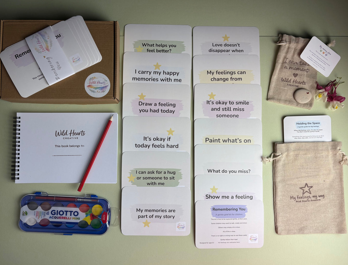 Remembering You grief support kit featuring reflection cards, creative activities, sketchbook, watercolour paints, comfort stone and drawstring pouch.