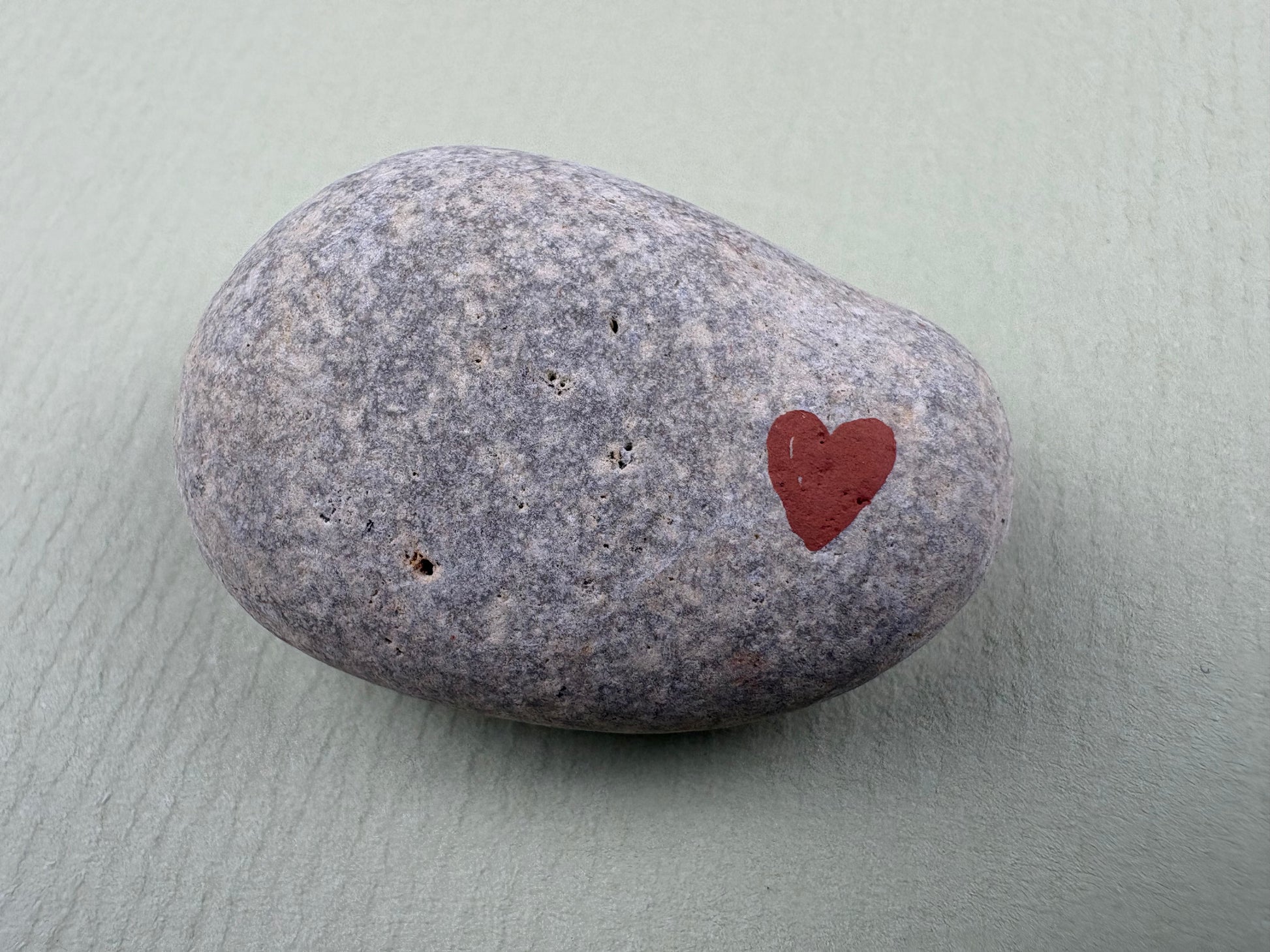 Close-up of a smooth grey comfort stone with a painted heart, designed by Wild Hearts Creative to help children feel calm, reassured and emotionally supported.