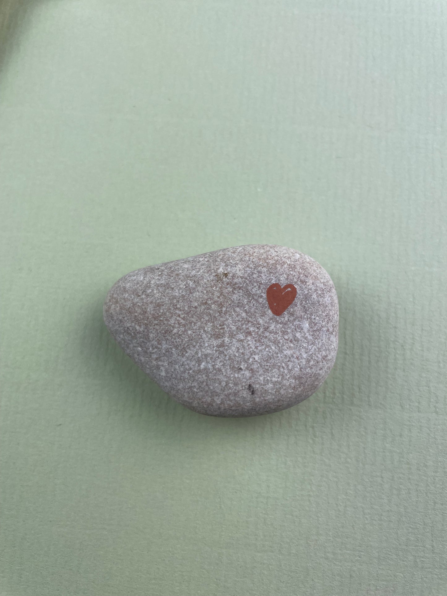 Gray stone with a red heart engraving on a light green background