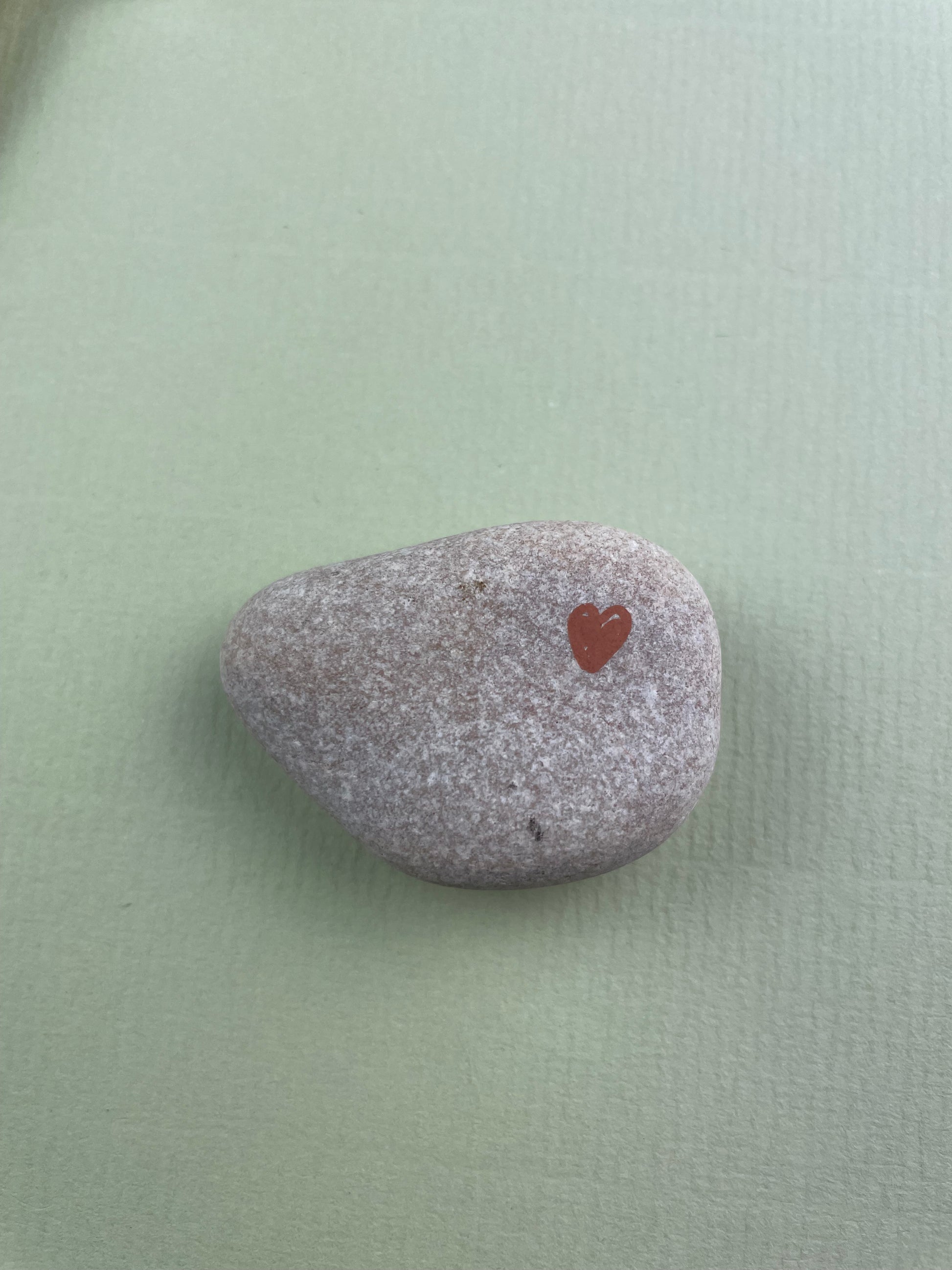 Gray stone with a red heart engraving on a light green background