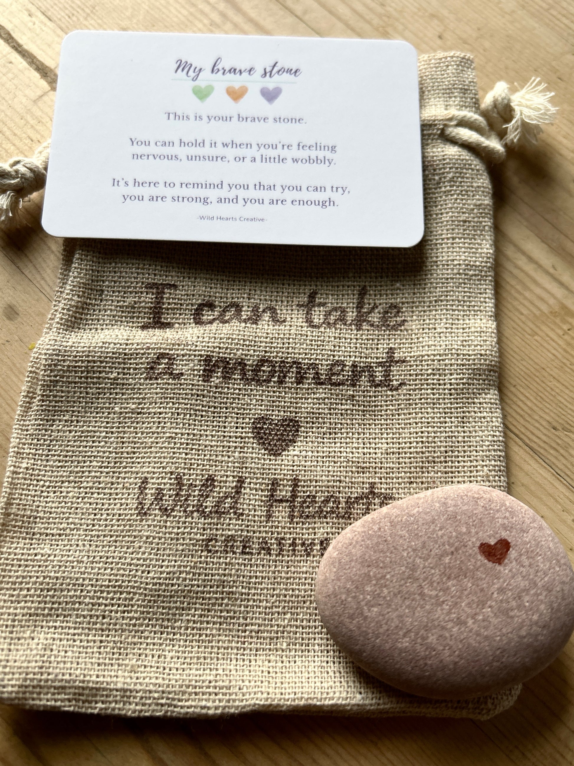 Decorative stone with bravery text and a card on a textured surface for children branded by wild hearts creative